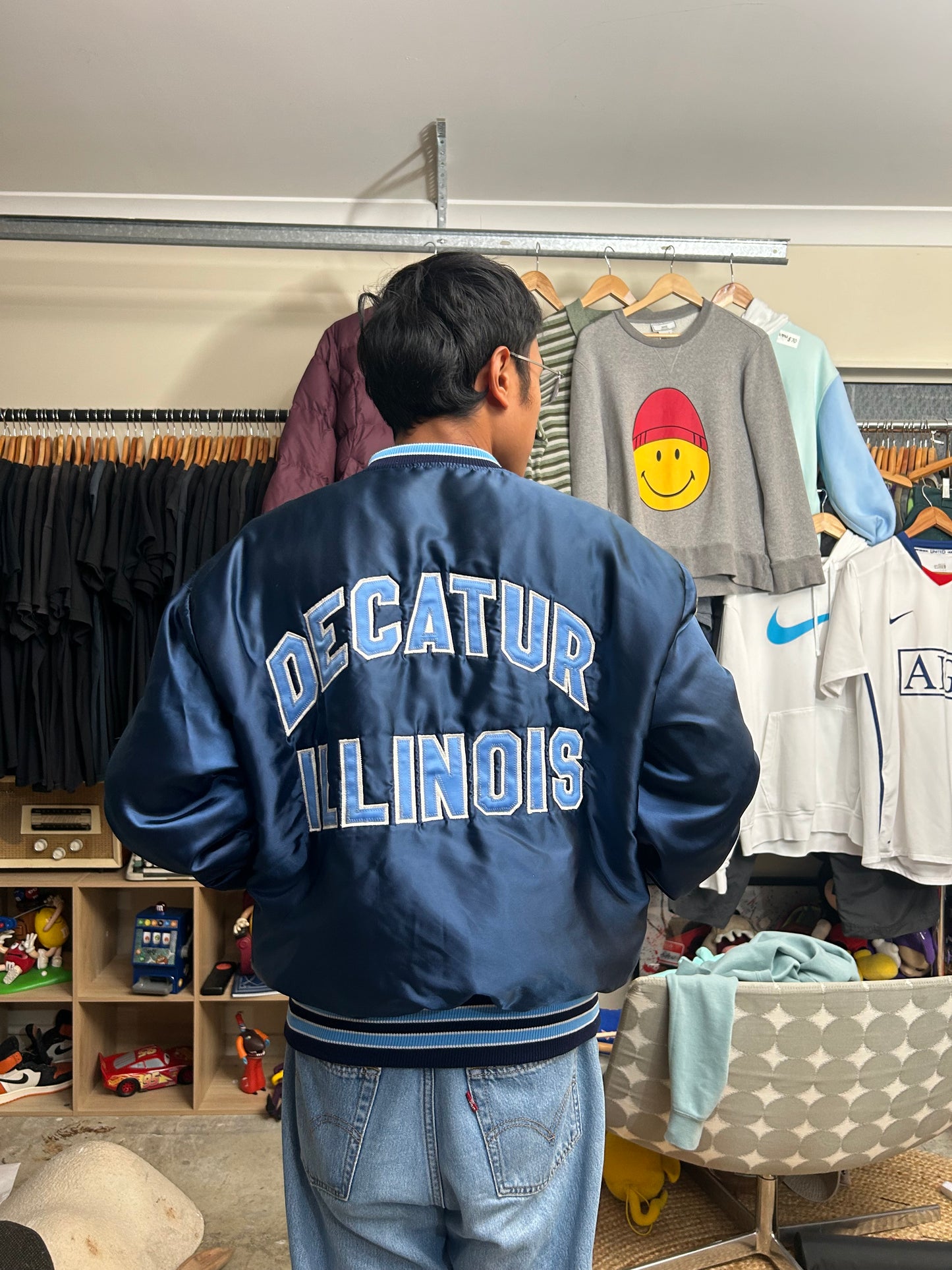 Vintage blue satin varsity bomber jacket features "Decatur Illinois" embroidered on the back in a light blue and white block font Large