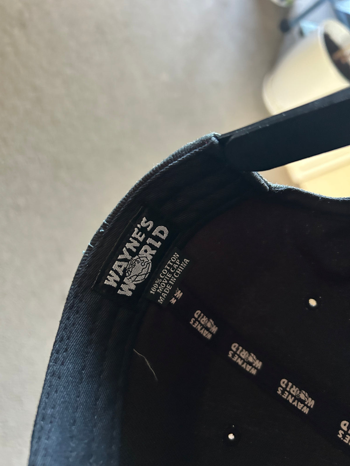 black Wayne's World snapback cap featuring white embroidered lettering and a globe graphic