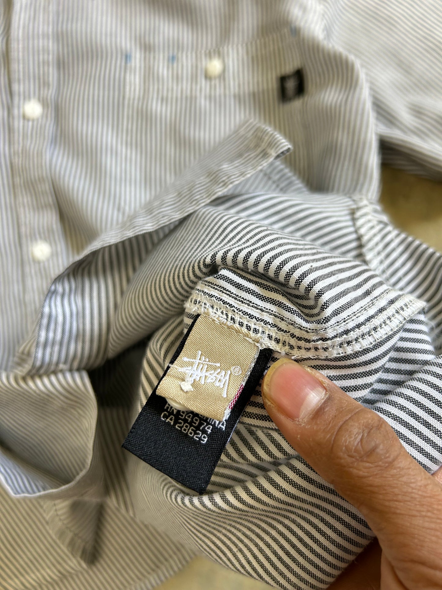 short-sleeve button-up shirt from the brand Stüssy, featuring a classic hickory stripe pattern and dual chest pockets.Medium