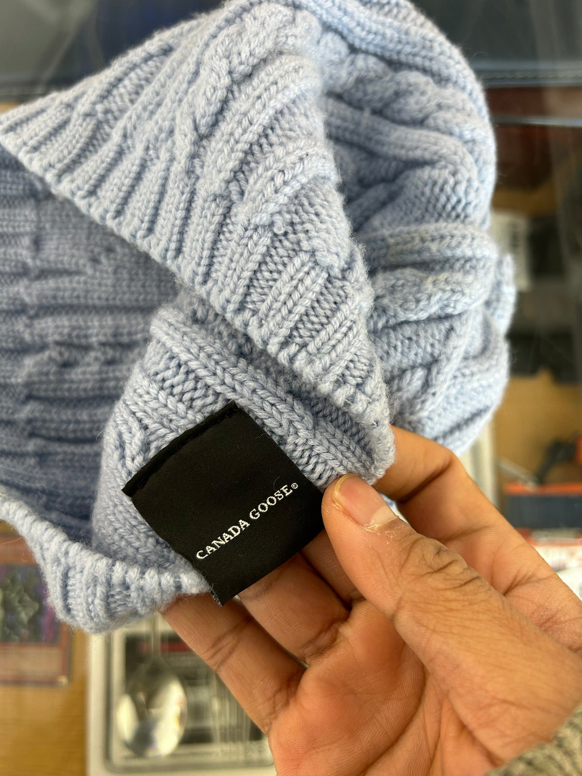 light blue or grey cable-knit wool beanie featuring a Canada Goose arctic disc logo patch on the front