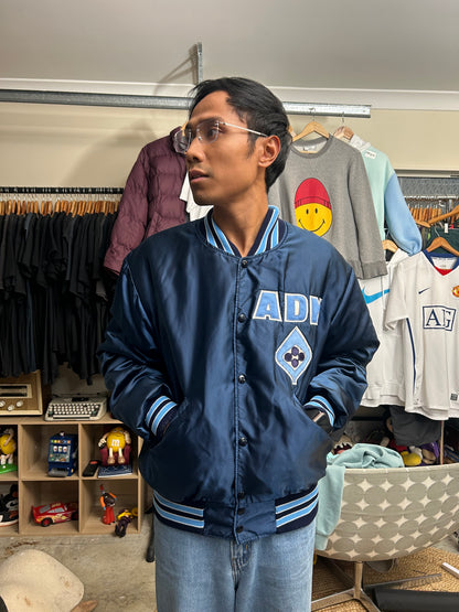 Vintage blue satin varsity bomber jacket features "Decatur Illinois" embroidered on the back in a light blue and white block font Large