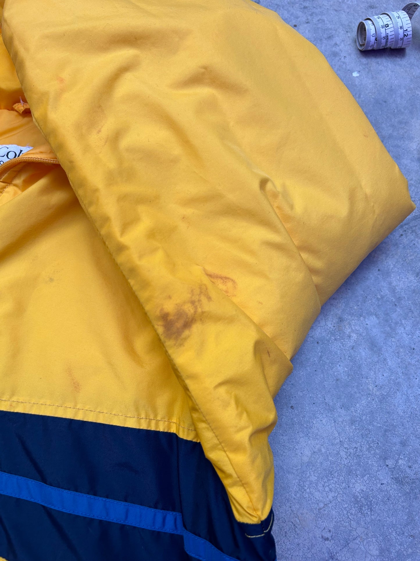 Medium vintage yellow Columbia Sportswear jacket with a blue stripe design across the chest. Has Stains