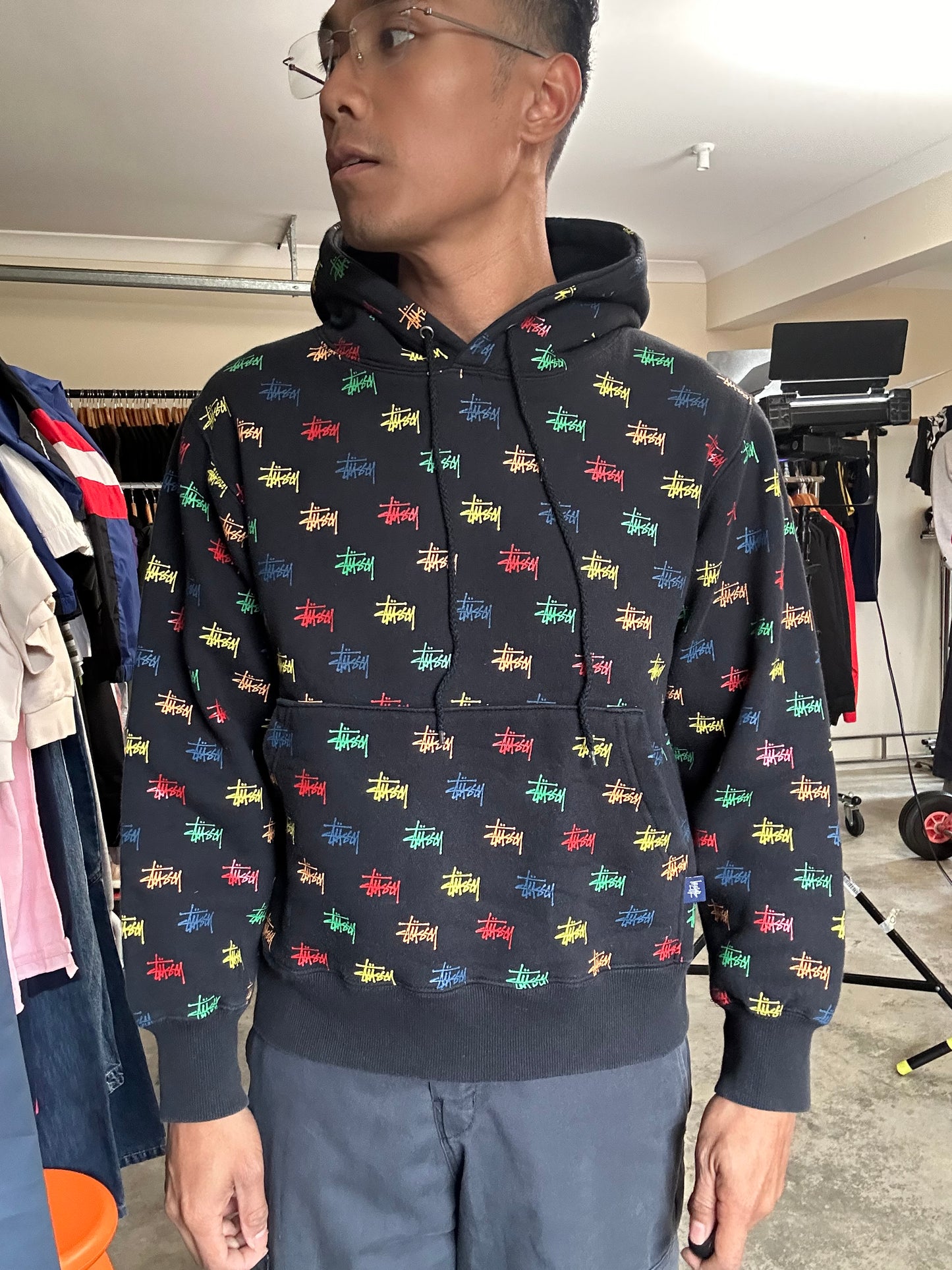 black, pullover-style hoodie featuring an all-over, multi-colored Stüssy logo print Small