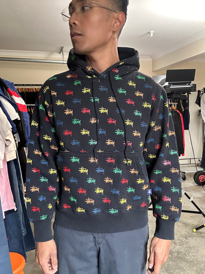 black, pullover-style hoodie featuring an all-over, multi-colored Stüssy logo print Small
