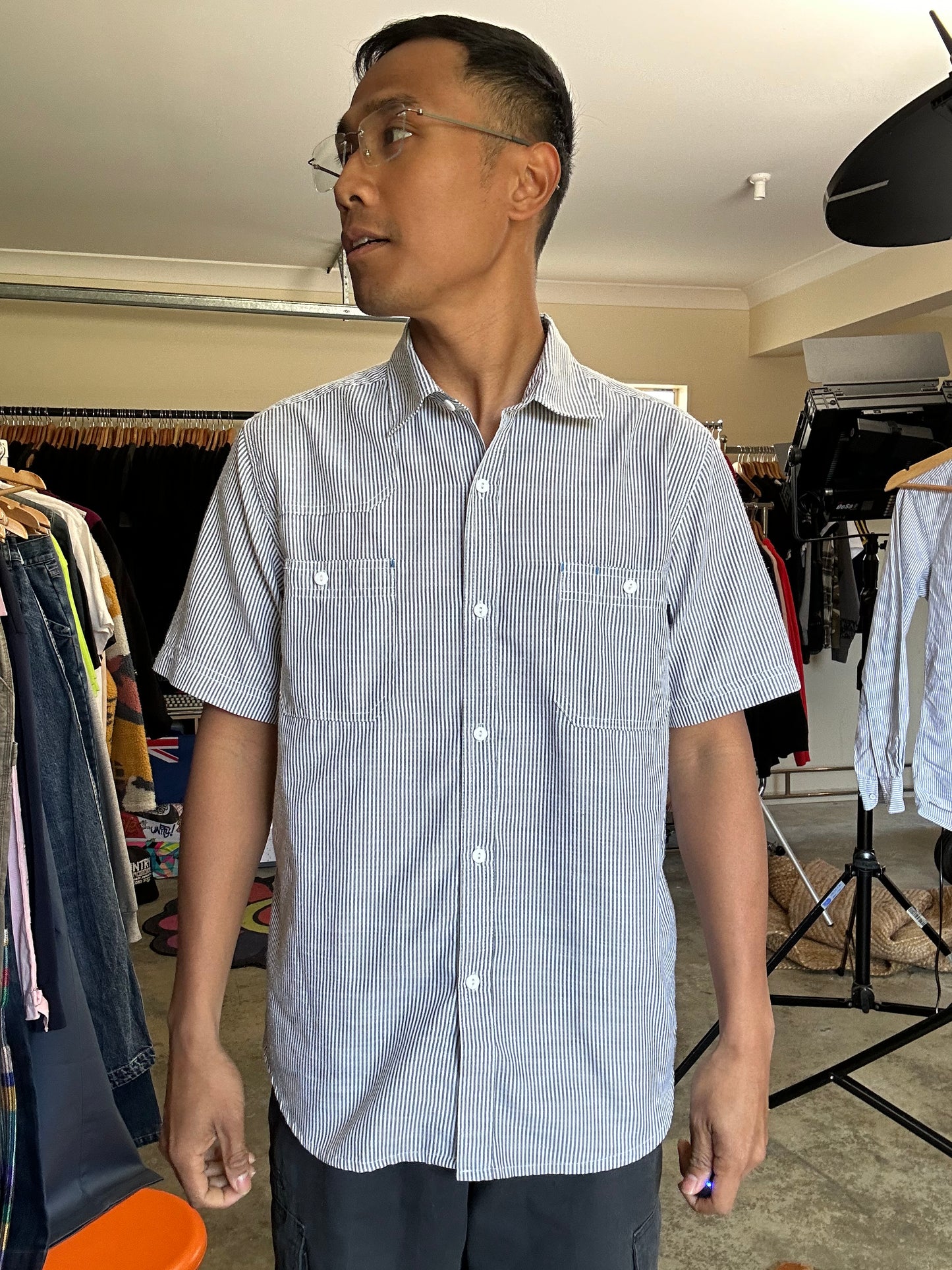 short-sleeve button-up shirt from the brand Stüssy, featuring a classic hickory stripe pattern and dual chest pockets.Medium