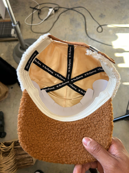 New Shepherds Sherpa Baseball Cap featuring a white fleece crown, a brown brim, and a gold embroidered 'B