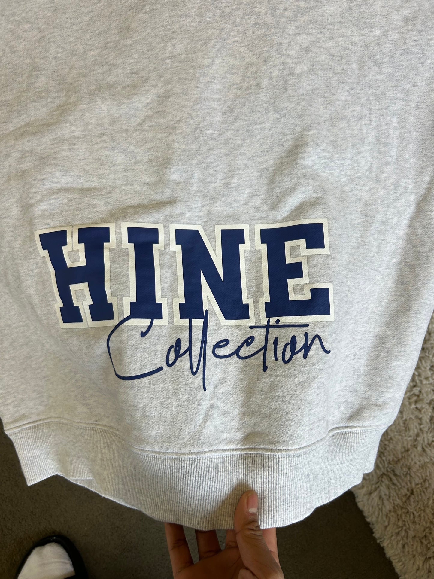 Hine Collection gray hoodie features a prominent navy blue "HC" embroidered logo on the chest