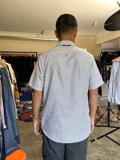 short-sleeve button-up shirt from the brand Stüssy, featuring a classic hickory stripe pattern and dual chest pockets.Medium