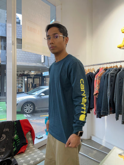 Carhartt Relaxed Fit Heavyweight Long-Sleeve Logo Sleeve Graphic T-Shirt in night blue heather with bold yellow lettering down the sleeve. Small