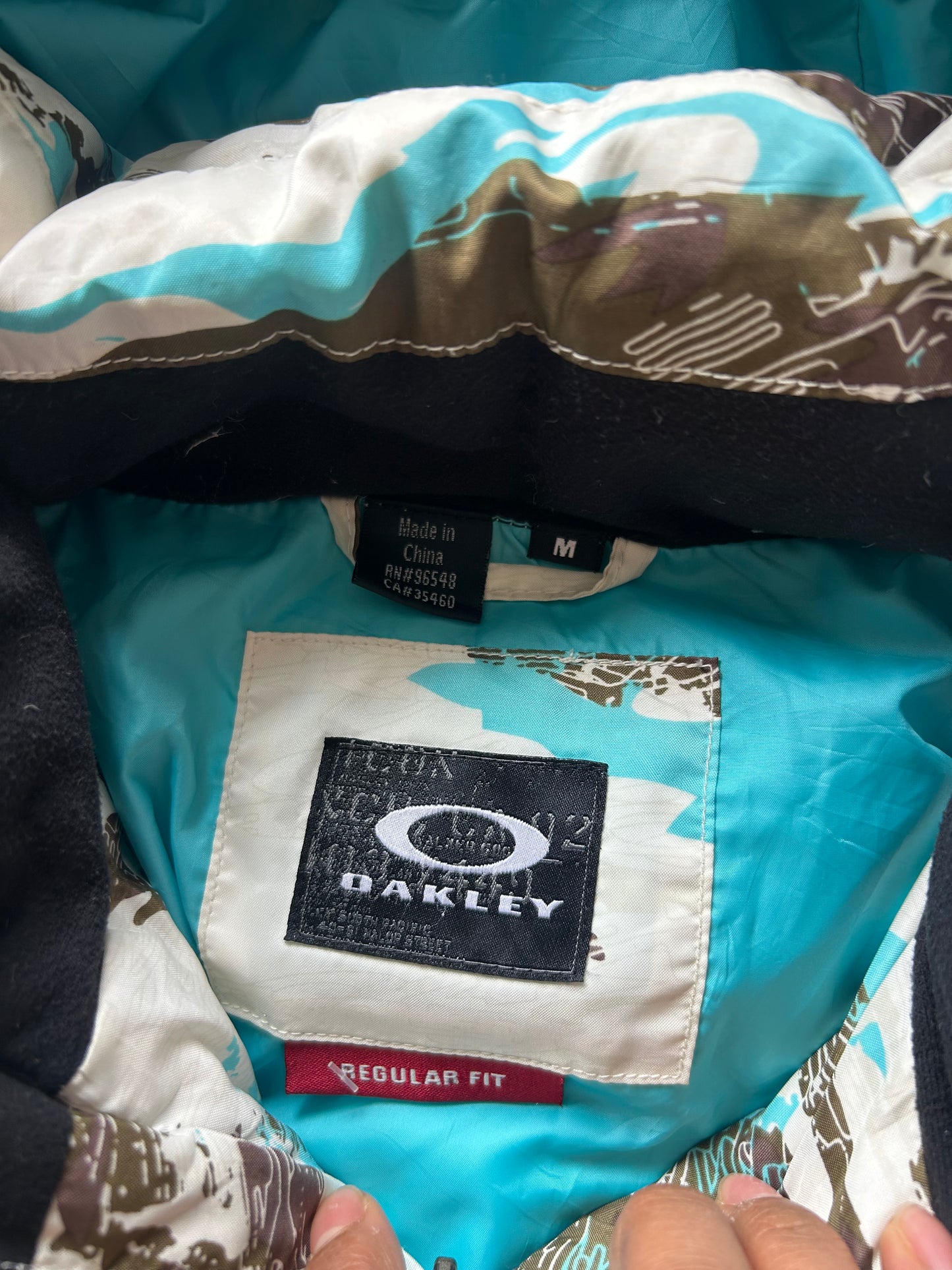 Oakley Avalanche NVL4 snow jacket in a white, brown, and blue camouflage pattern Large
