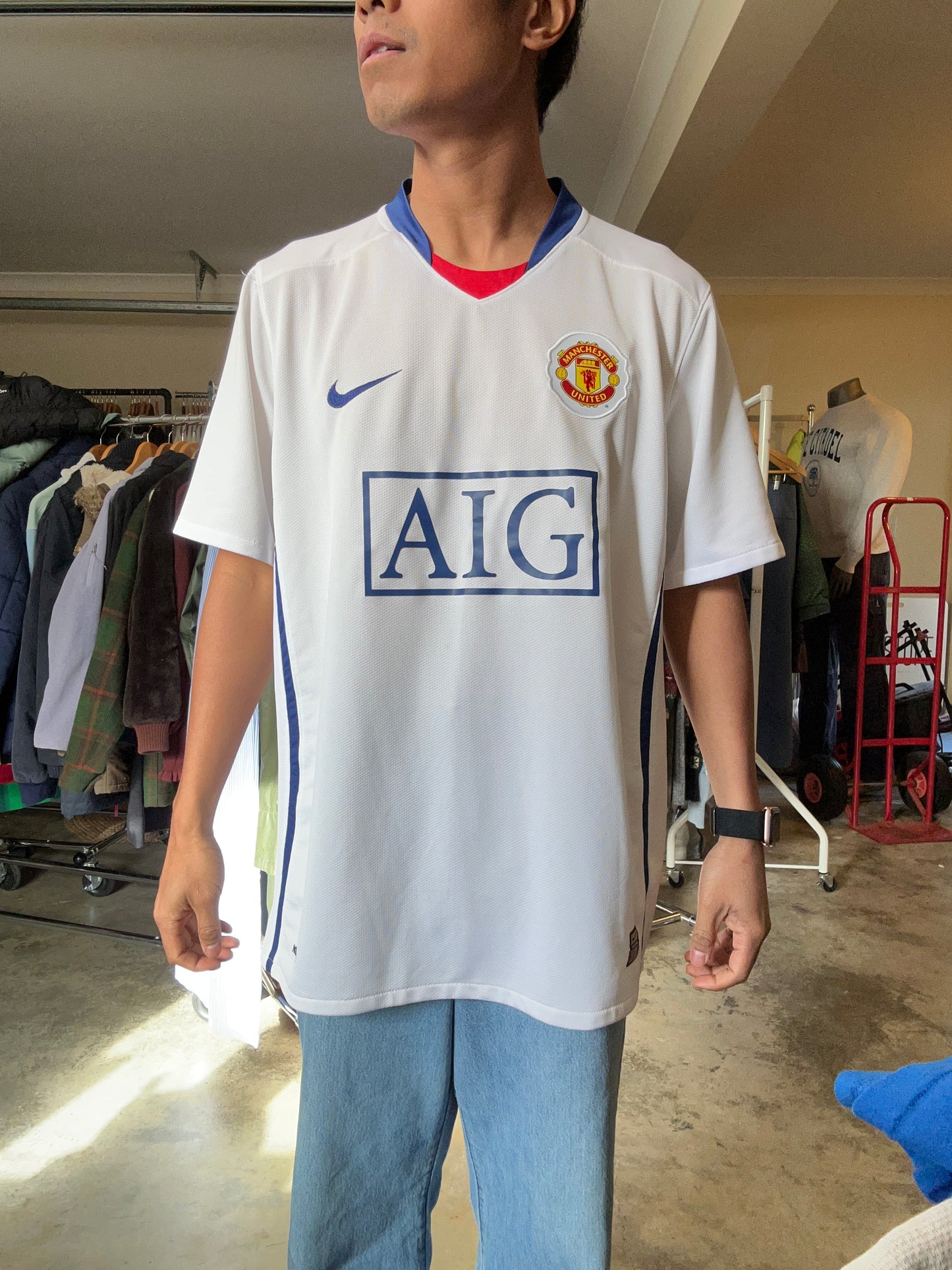 Nike Manchester United away jersey from the 2008-2009 season, featuring a classic white design with a blue V-neck and "AIG Large White
