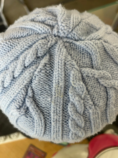 light blue or grey cable-knit wool beanie featuring a Canada Goose arctic disc logo patch on the front