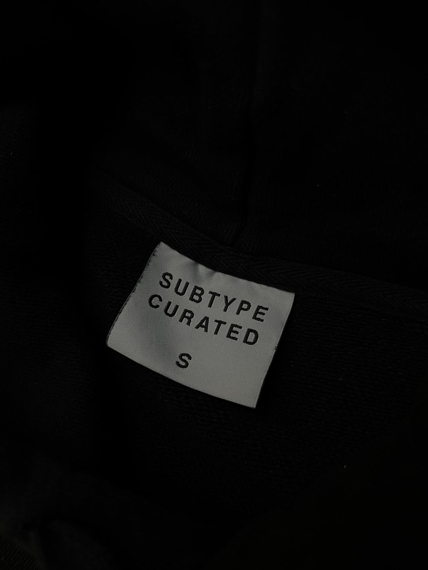 black Subtype Curated hoodie features a prominent kangaroo pocket and a clean, minimalist design Small