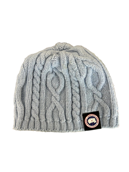 light blue or grey cable-knit wool beanie featuring a Canada Goose arctic disc logo patch on the front