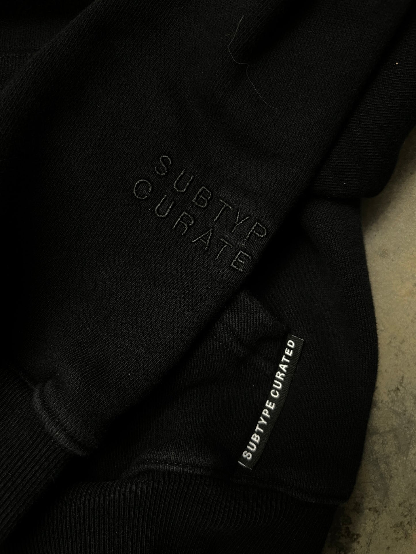 black Subtype Curated hoodie features a prominent kangaroo pocket and a clean, minimalist design Small