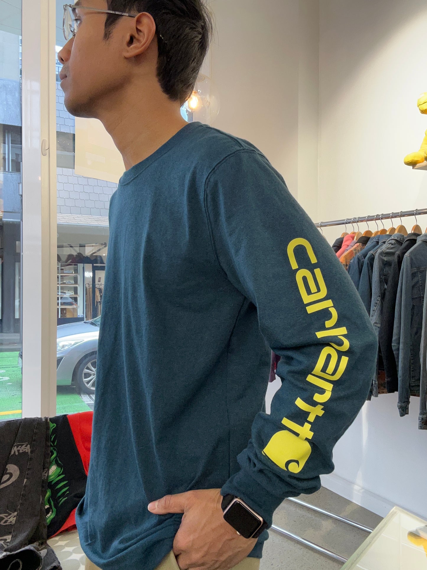 Carhartt Relaxed Fit Heavyweight Long-Sleeve Logo Sleeve Graphic T-Shirt in night blue heather with bold yellow lettering down the sleeve. Small