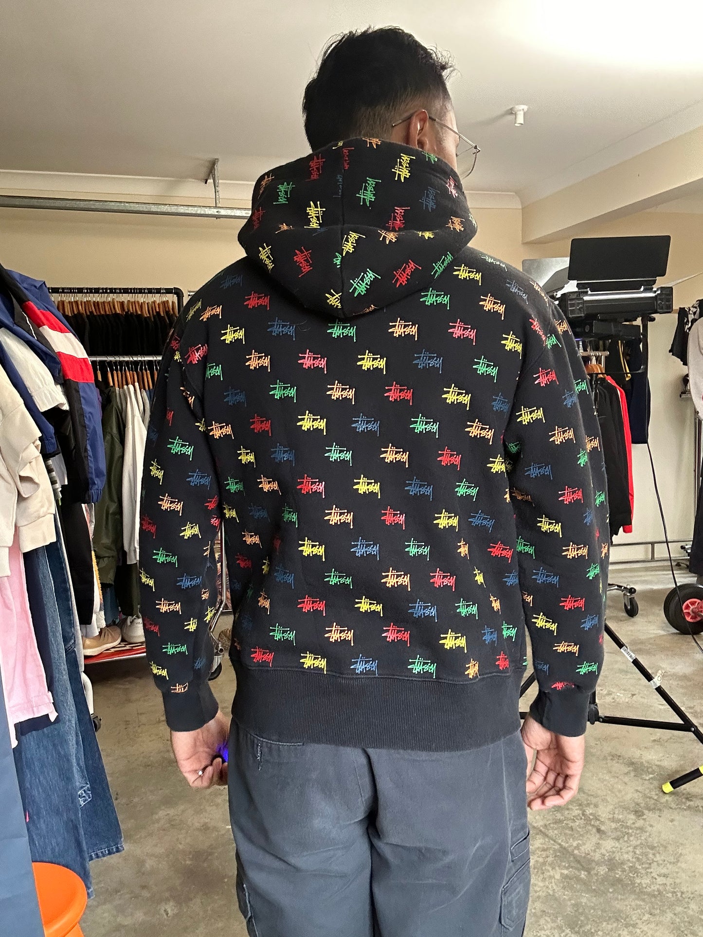 black, pullover-style hoodie featuring an all-over, multi-colored Stüssy logo print Small