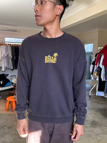 Faded black sweatshirt is a Billabong crewneck featuring a yellow palm tree logo on the chest Large