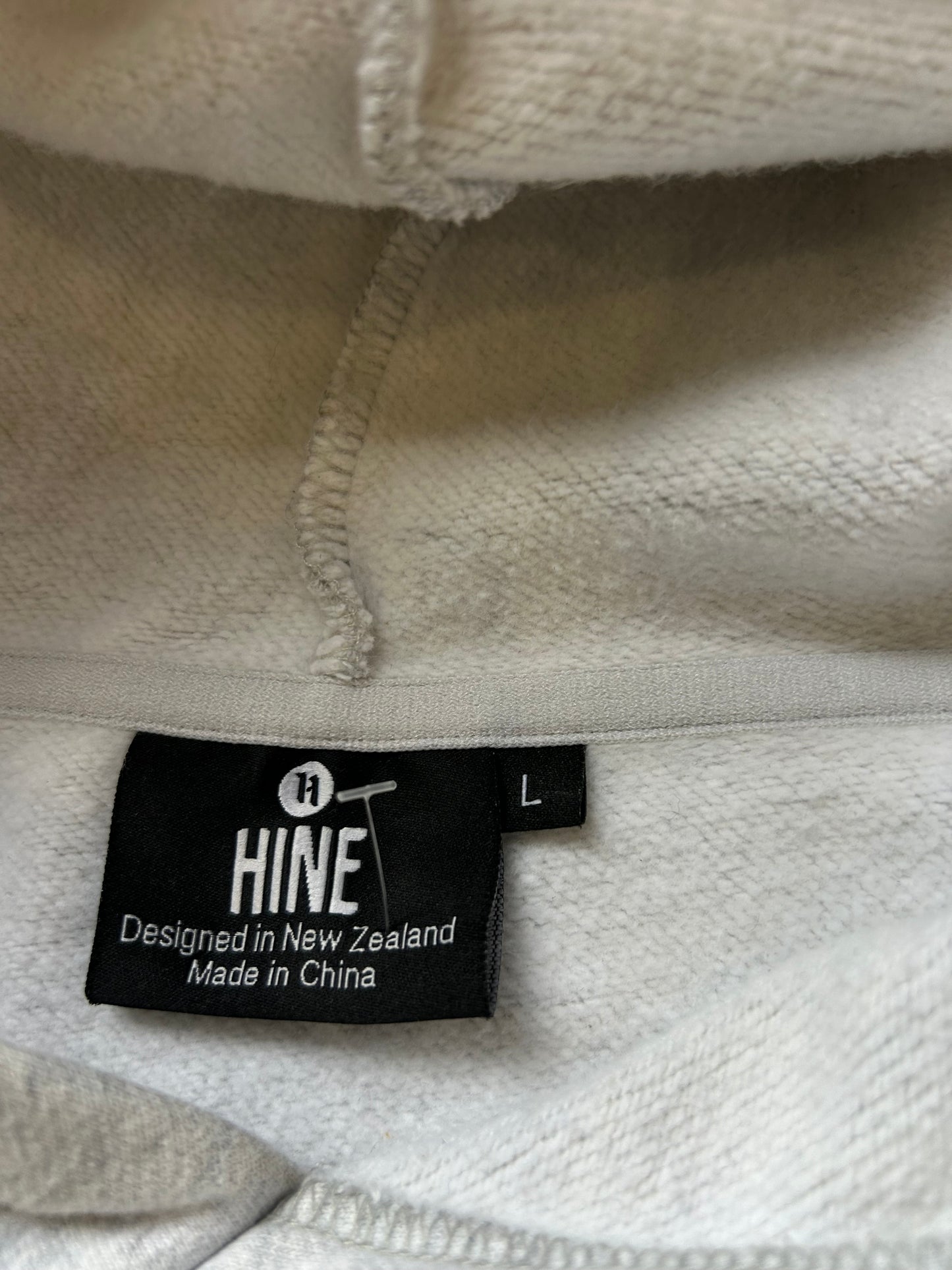 Hine Collection gray hoodie features a prominent navy blue "HC" embroidered logo on the chest