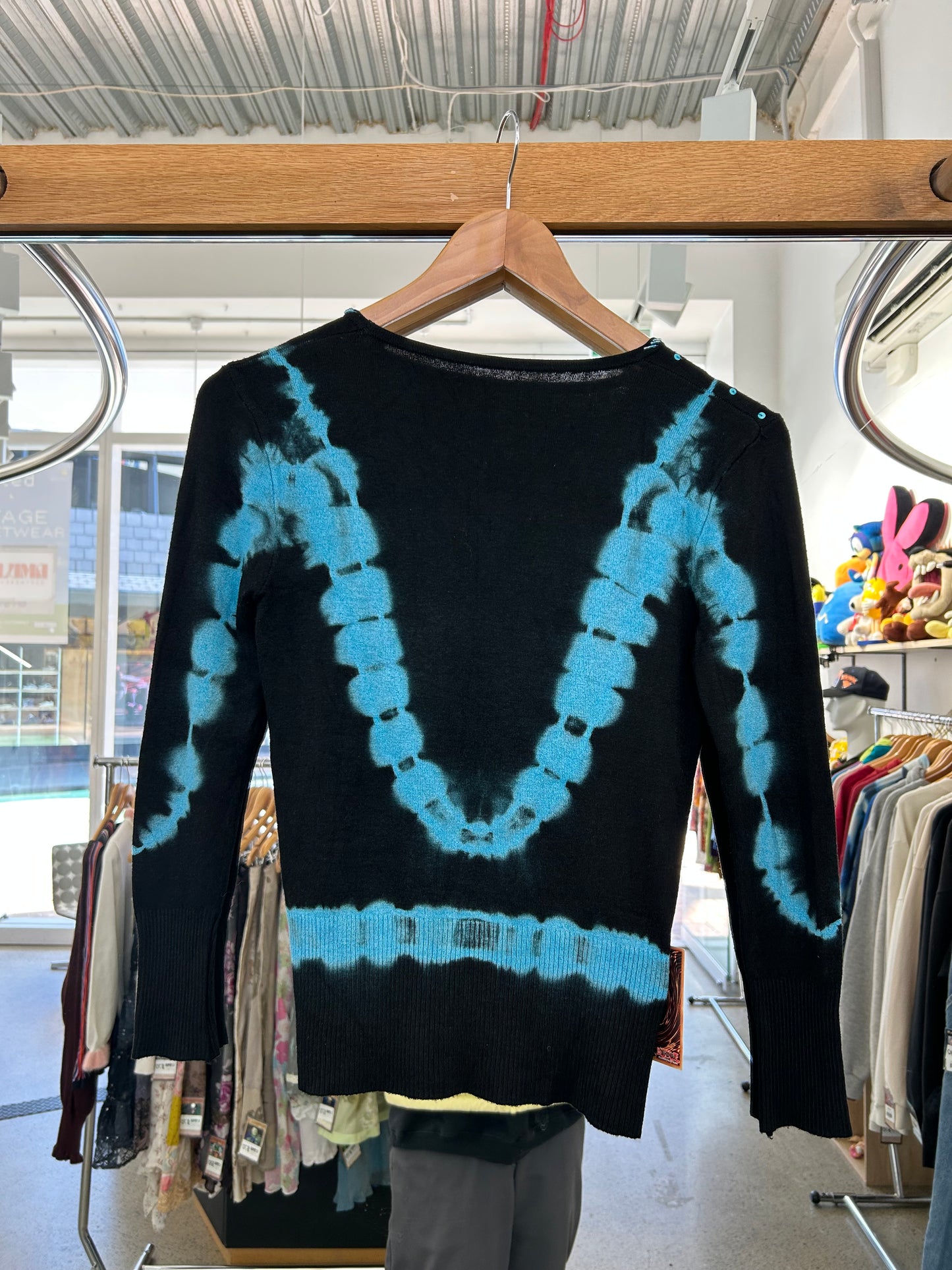black knit sweater features blue tie-dye accents and floral embroidery with beaded details.